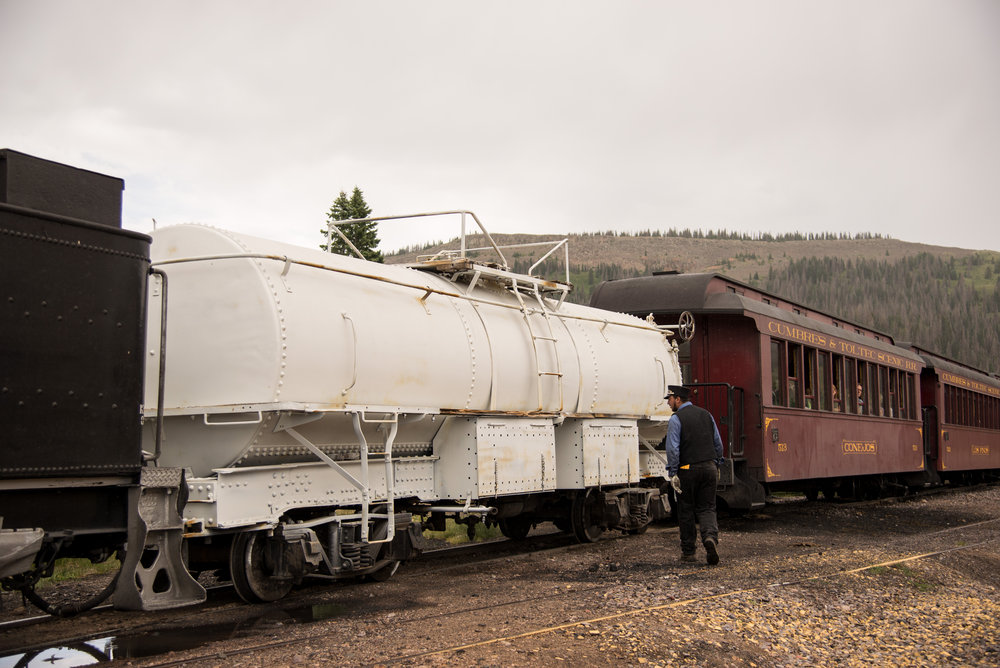 45 One of the train crew is looking at a water tank car coming back to Chama from Antonito.jpg