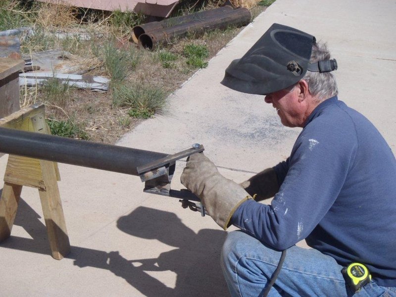 Russ Hanscom is welding structural post to uphold roof of car shelter.jpg