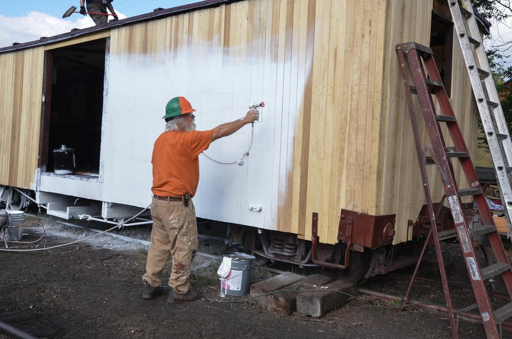 2018-07-31 Brad is spraying the primer on the sides as work on the roof continues.jpg