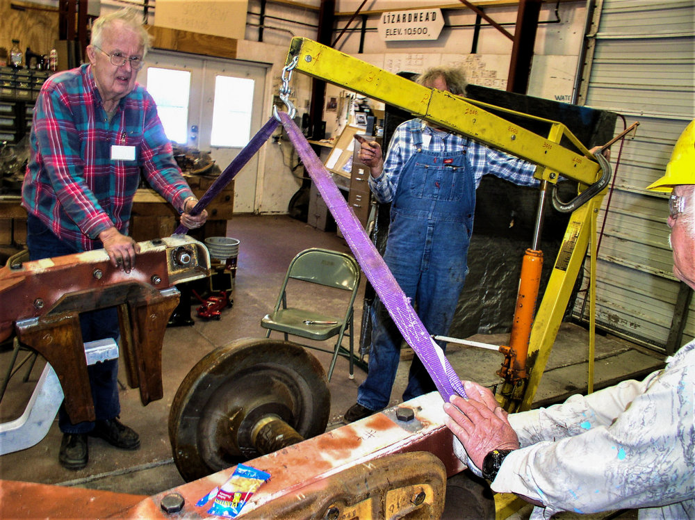 The crew working on the passenger car trucks is about to set a wheel under the frame.jpg