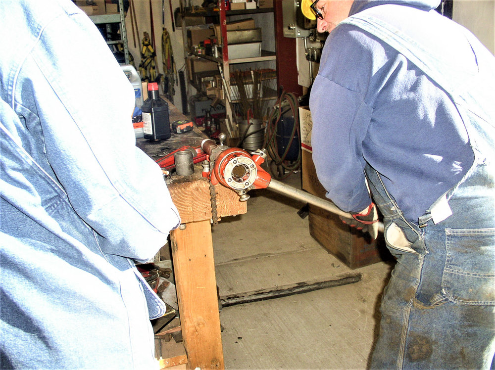 A length of pipe is getting threads cut into it.jpg