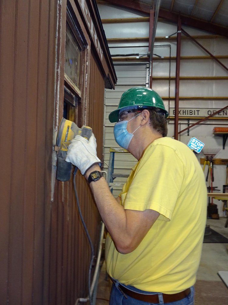 Using the orbital sander on the outside of a window on the caboose.jpg