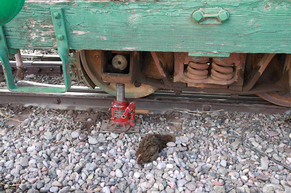 Hand press under the journal box of the green car with some of the old packing on the ground (1 of 1).jpg