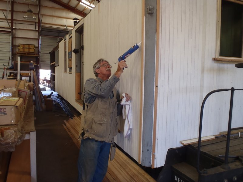 Team Leader Craig McMullen caulks siding on Cook Car 053.jpg